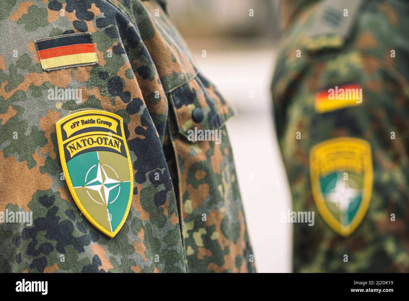 Drapeau de l'Allemagne et symbole du groupe de combat de l'OTAN sur un uniforme de soldat avec fusil de chasse ou fusil, unité d'intégration de la force de l'OTAN, gros plan Banque D'Images