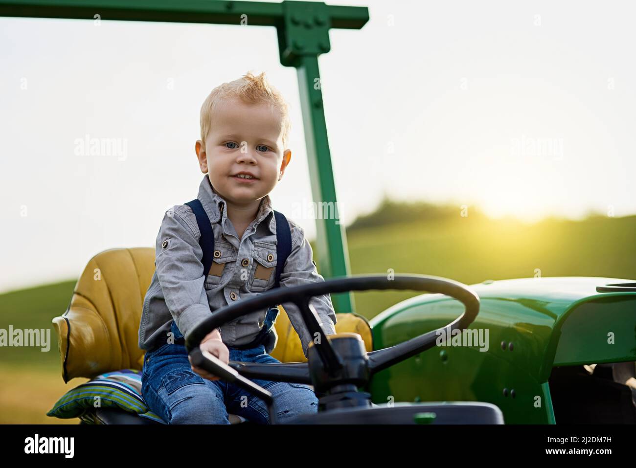 Grandir avec de bonnes valeurs agricoles à l'ancienne. Portrait d'un adorable petit garçon à bord d'un tracteur sur une ferme. Banque D'Images