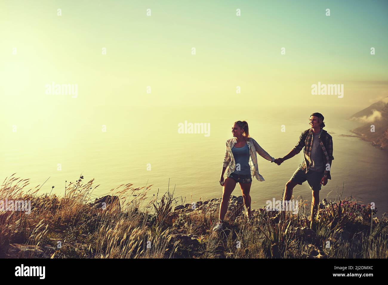 Explorons le chemin moins parcouru. Photo d'un jeune couple affectueux qui se joint lors d'une randonnée ensemble. Banque D'Images