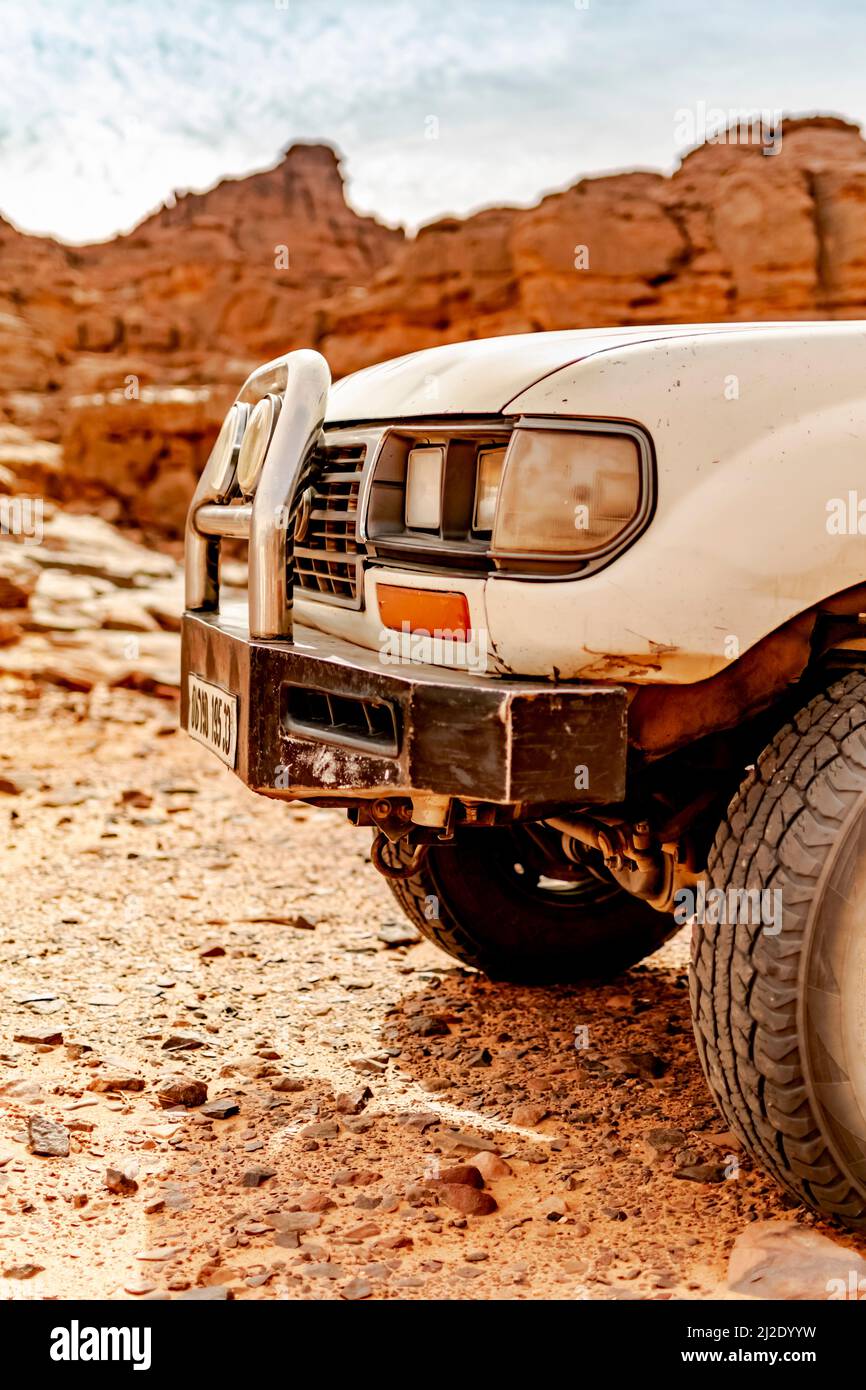 Face avant d'une voiture 4x4 dans le désert reg. Côté gauche de la partie avant d'une voiture à quatre roues motrices garée dans le reg avec des pierres sèches dans le Sahara. Banque D'Images