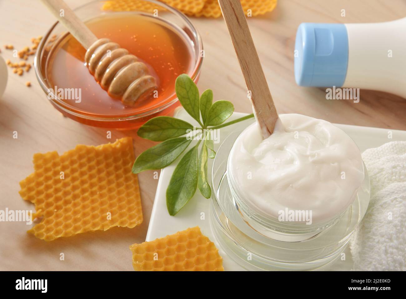 Produits cosmétiques d'hygiène personnelle avec extraits de miel sur table en bois avec récipient avec miel et cire de nid d'abeille autour d'elle dans une salle de bains. Élévation supérieure Banque D'Images