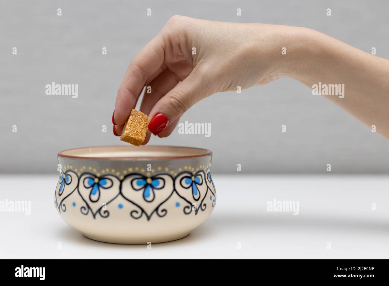 la main d'une femme sort un cube de sucre brun d'un bol à sucre. Photo de haute qualité Banque D'Images