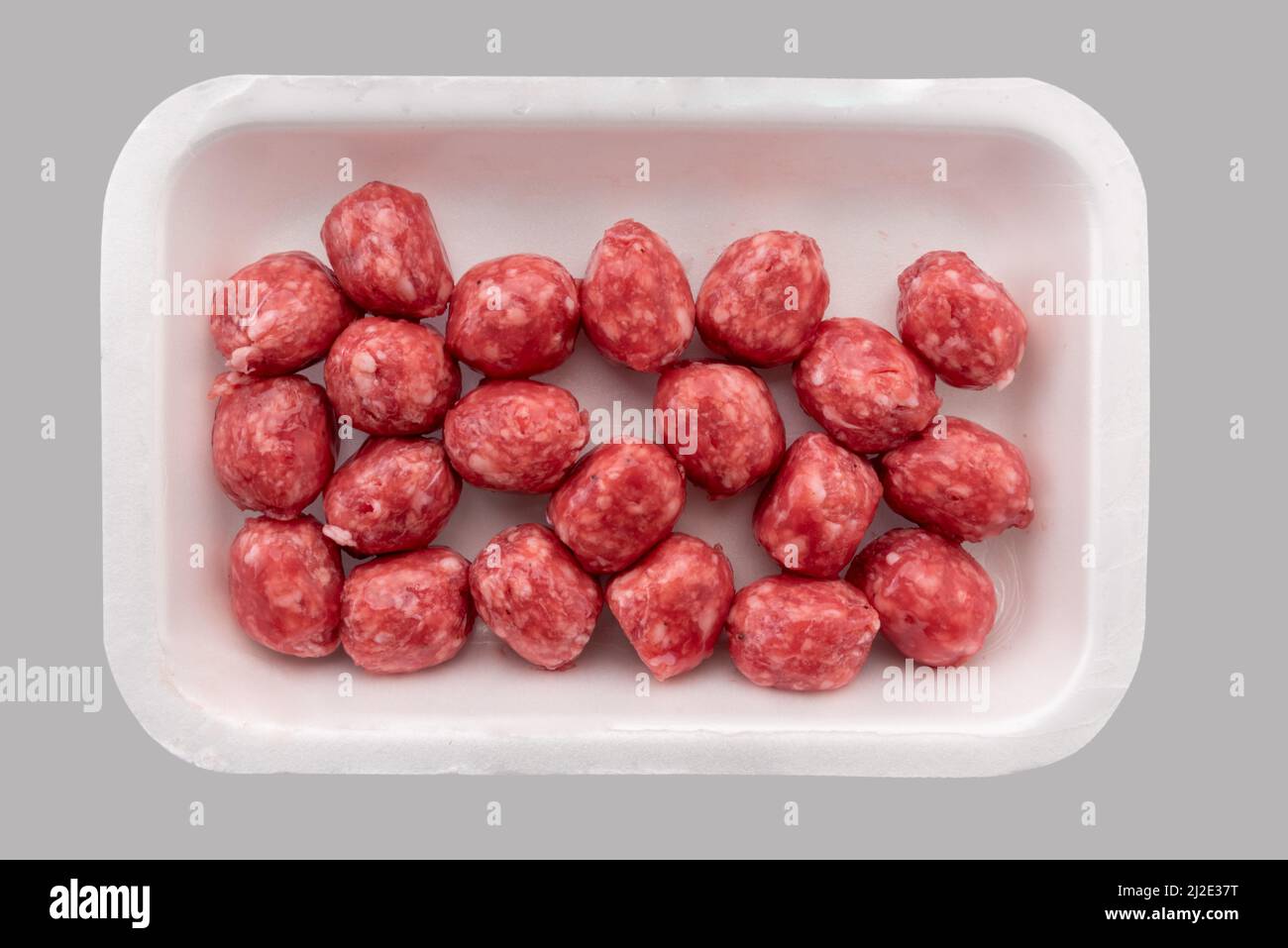 Boulettes de viande de bœuf cru dans un plateau en plastique alimentaire à vendre au supermarché, isolé sur fond gris clair, chemin de coupure, vue de dessus Banque D'Images