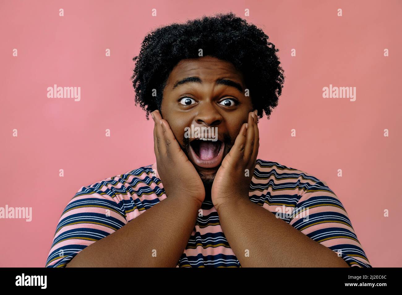 jeune homme afro-américain heureux posant dans le studio sur fond rose modèle masculin Banque D'Images
