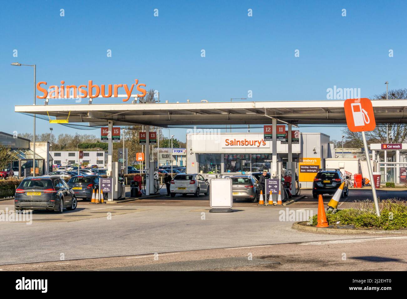 Voitures approchant des pompes à essence sur la piste d'une station-service dans un supermarché Sainsbury. Banque D'Images