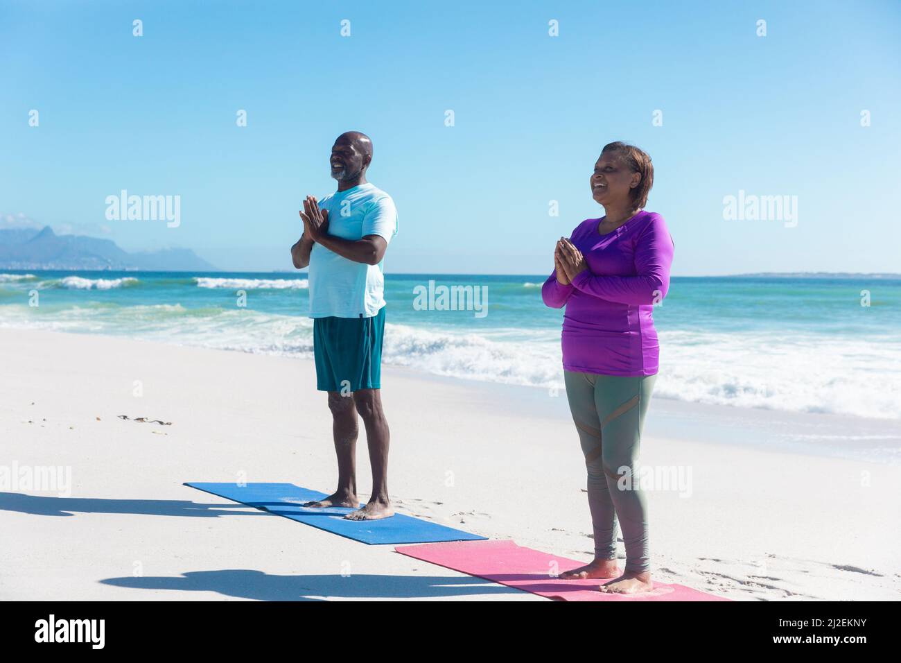 FIT african american senior couple pratiquant le yoga à la plage contre le ciel bleu le jour ensoleillé Banque D'Images