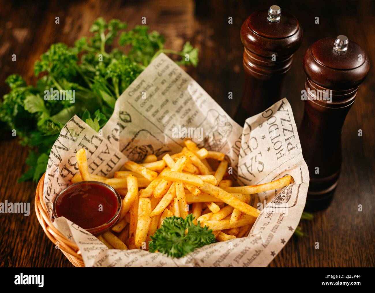 Portion de frites et sauce ketchup. Plats de bar servis dans un panier. Frites croustillantes avec feuilles de persil. Banque D'Images