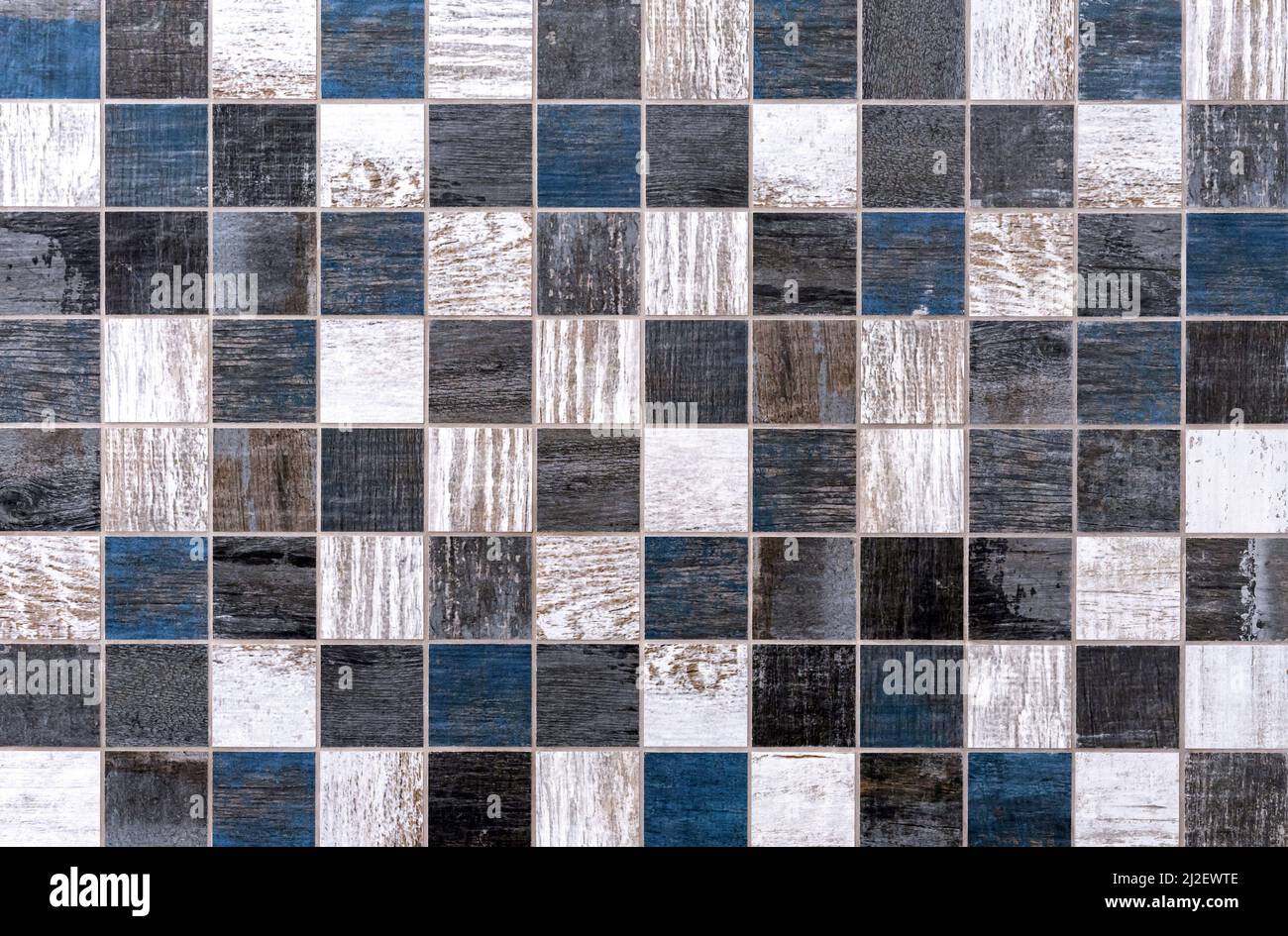 Mosaïque de céramique avec des carrés gris, bleus et blancs et une structure en imitation de bois. Banque D'Images
