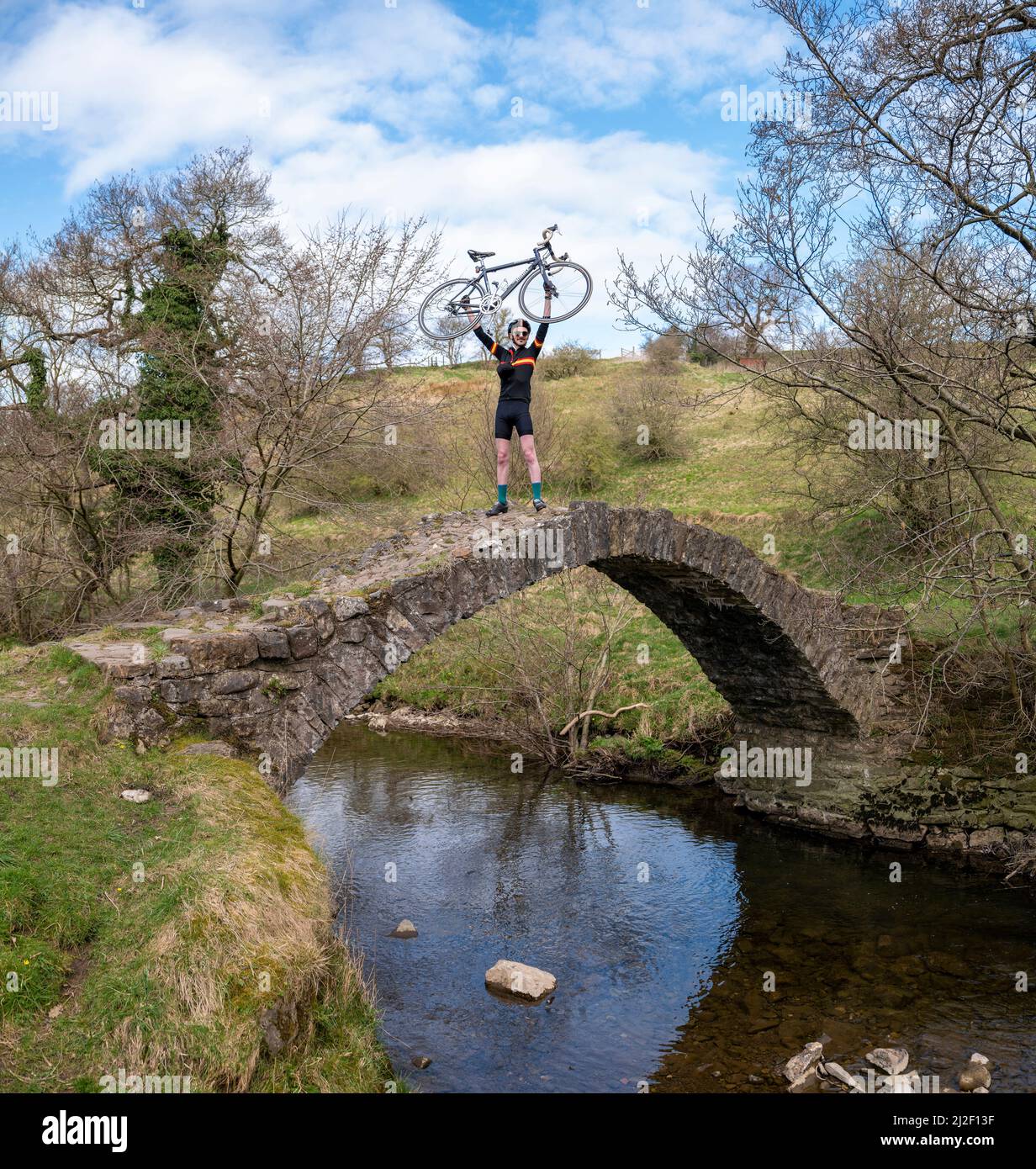 Cycliste masculin avec Ribble cycles à vélo célébrant sur Fairy Bridge, Downham, Lancashire, Royaume-Uni. Banque D'Images