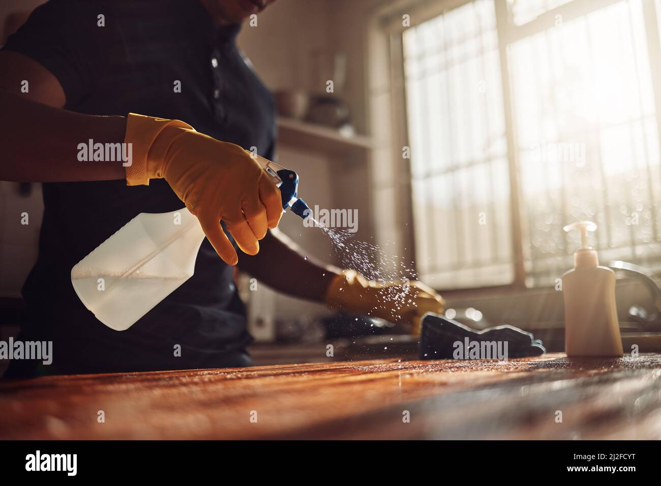 Je n'ai pas besoin d'une baguette magique, j'ai eu mes mains. Photo d'un homme méconnaissable désinfectant un comptoir de cuisine à la maison. Banque D'Images