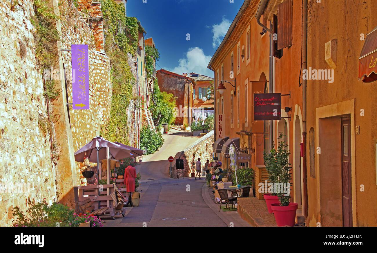 Roussillon en Provence, France - octobre 2. 2019: Vue sur la rue avec mur de pierre naturelle de la forteresse et des maisons jaunes ocre méditerranéennes contre blu Banque D'Images