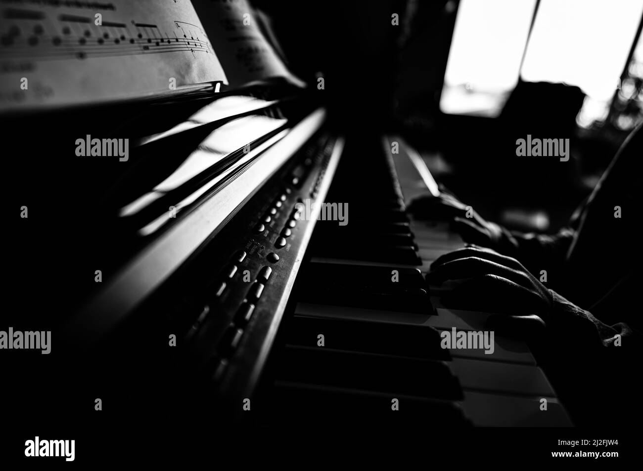 Jeune enfant s'exerçant à jouer un piano avec les mains reposant sur les clés Banque D'Images