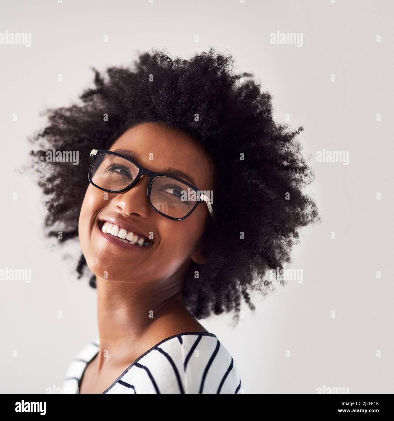 Aussi heureux et insouciant que possible. Photo en studio d'une jeune femme attrayante et heureuse portant des lunettes sur fond gris. Banque D'Images