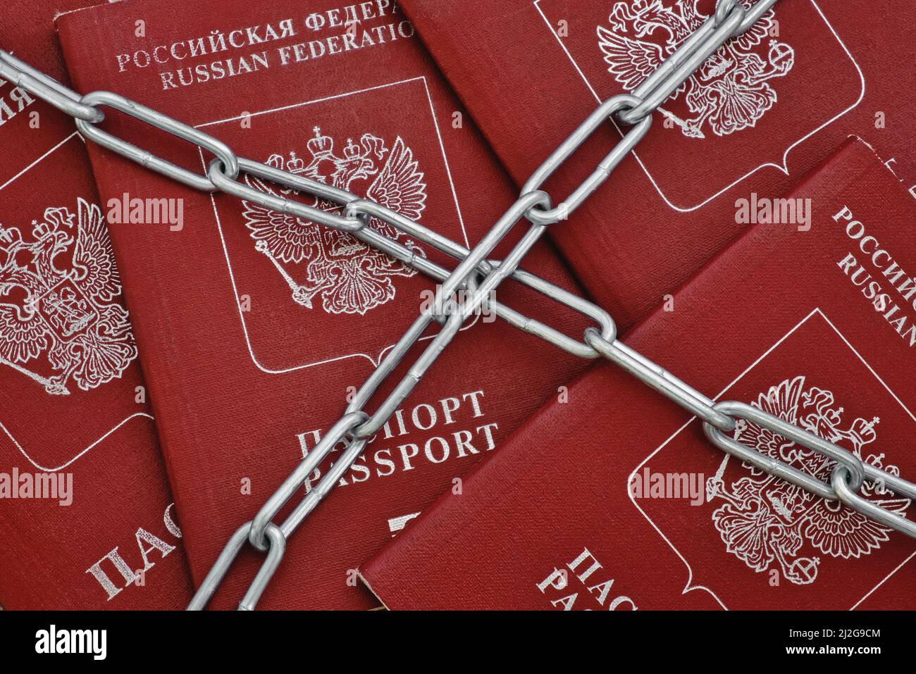 Chaîne métallique sur les passeports avec couvercles rouges. Sanctions et concept de rideau de fer. Banque D'Images
