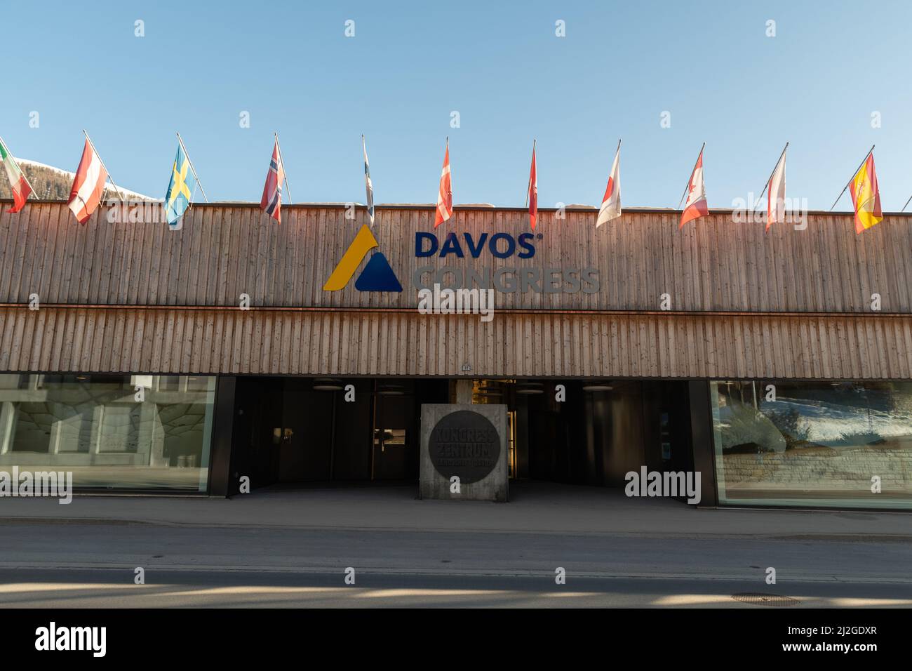 Davos, Suisse, le 23 mars 2022, différents drapeaux nationaux agités par-dessus l'entrée du palais des congrès par une journée ensoleillée Banque D'Images