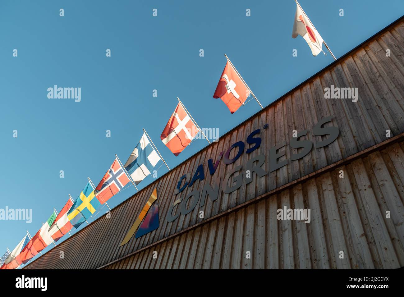 Davos, Suisse, le 23 mars 2022, différents drapeaux nationaux agités par-dessus l'entrée du palais des congrès par une journée ensoleillée Banque D'Images