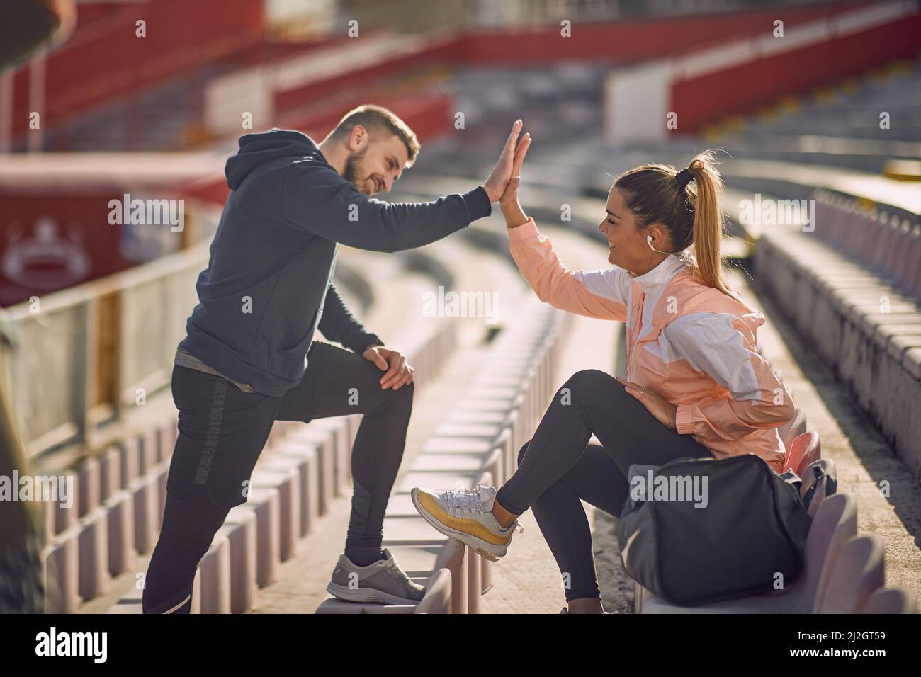 beardy guy et belle femme donnant des hauts-cinq les uns aux autres au stade dans les vêtements de sport, souriant Banque D'Images