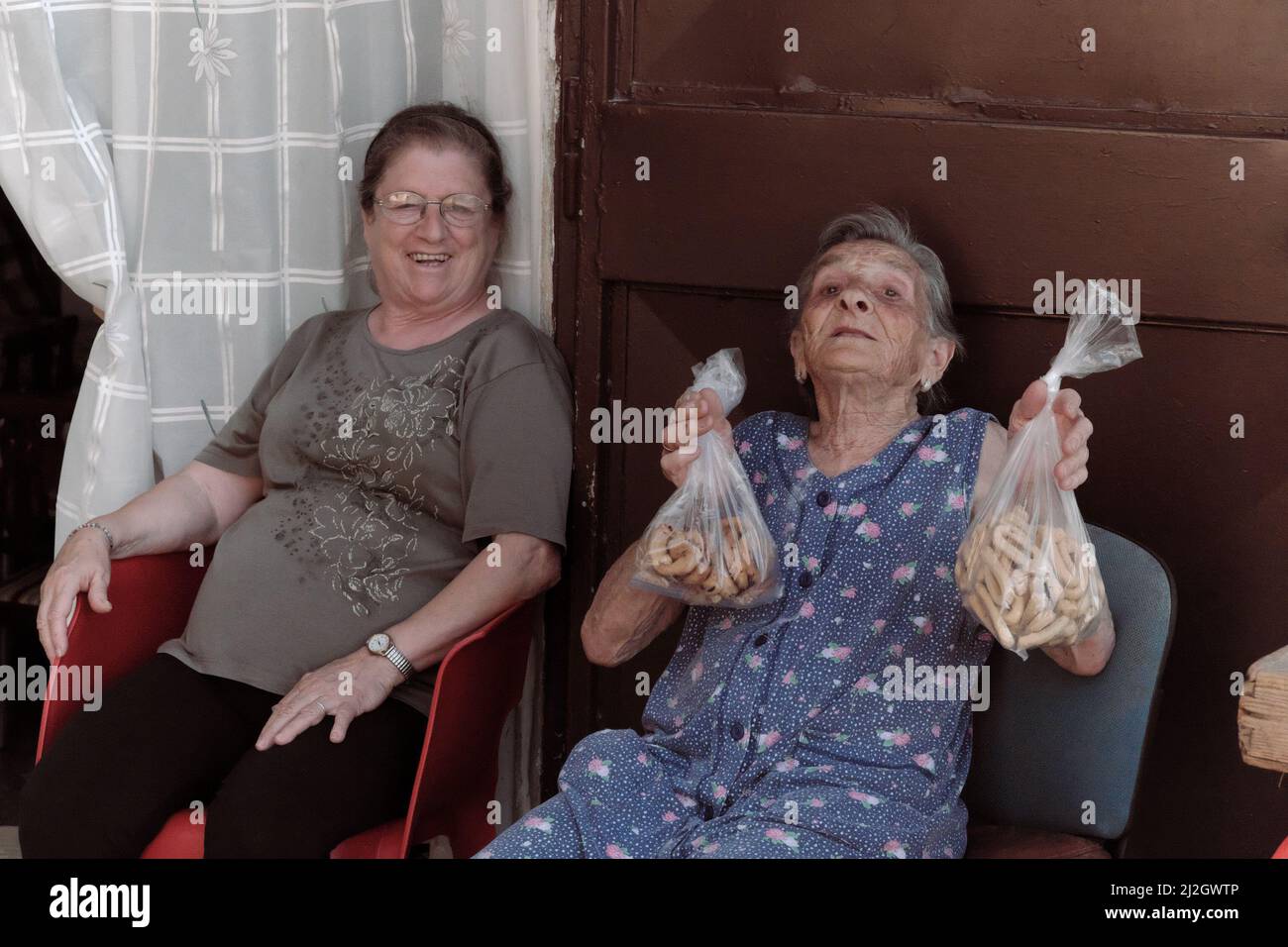 BARI, ITALIE - 11 JUILLET 2017: Dans les ruelles de la vieille ville de Bari, une femme âgée me montre deux sacs de parents avec des biscuits faits maison qui vend assis dans t Banque D'Images