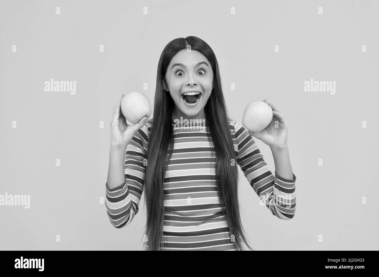 Une fille excitée tient des pommes pour des dents saines fond jaune, régime dentaire Banque D'Images