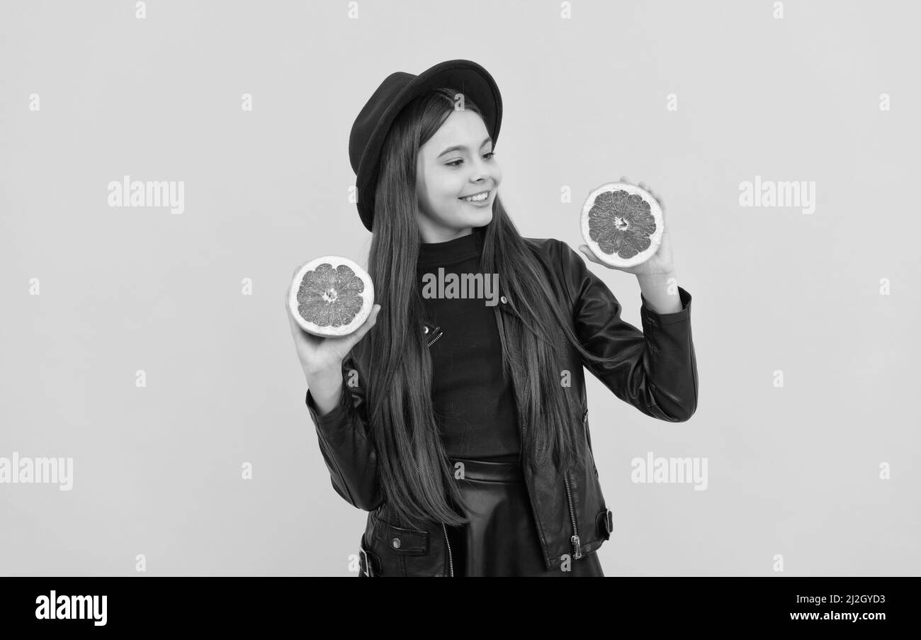 bonne adolescente en chapeau et veste en cuir tenir le pamplemousse coupé, vitamine Banque D'Images