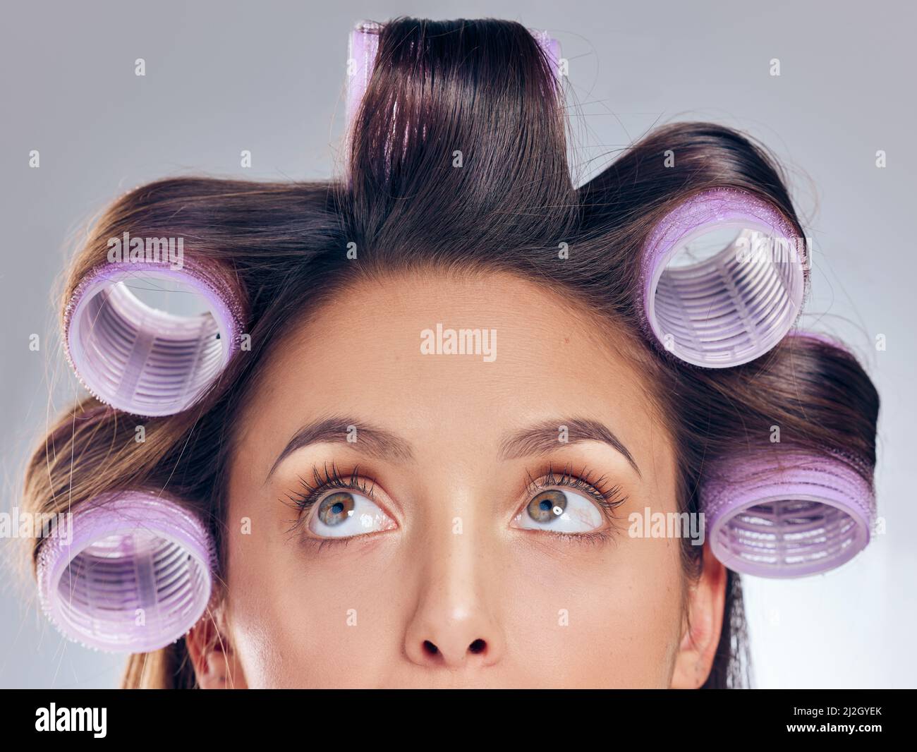 Soyez des vagues parfaites. Coupe courte d'une jeune femme attrayante debout seule dans le studio et posant avec des rouleaux dans ses cheveux. Banque D'Images