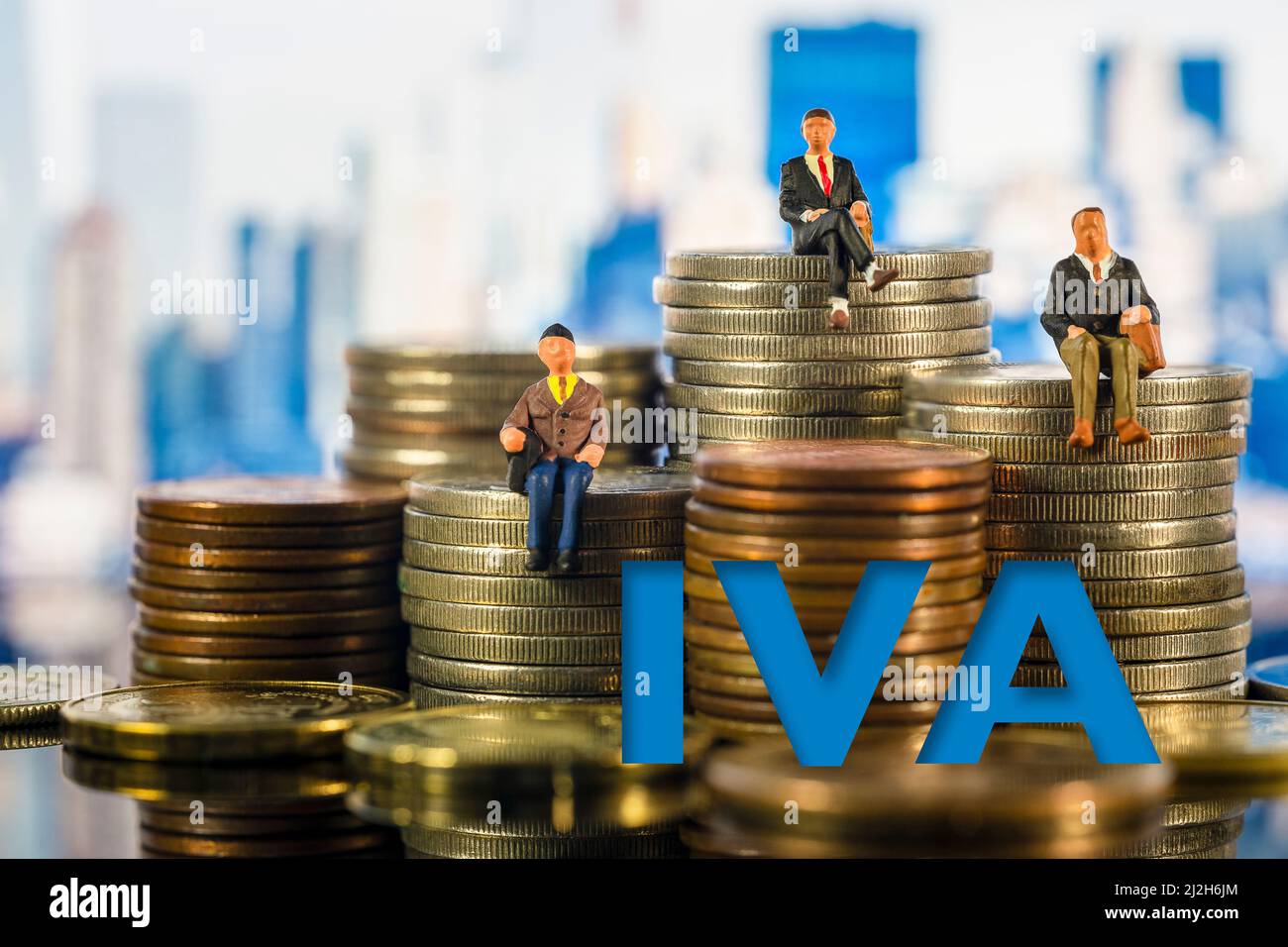Des gens miniatures : de petits hommes d'affaires assis sur des piles de pièces. Concept de fiscalité. Les lettres IVA (taxe espagnole sur la valeur ajoutée) sur les dés sur les piles de l'or co Banque D'Images