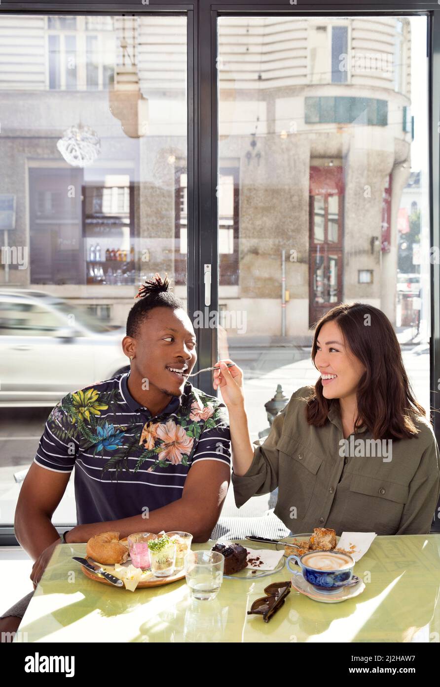 Couple souriant partageant la nourriture au restaurant Banque D'Images