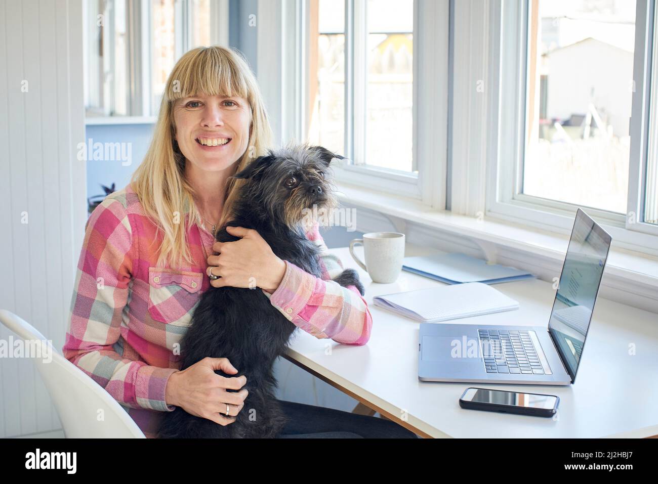 Portrait d'une femme mûre tenant son chien et travaillant à la maison Banque D'Images