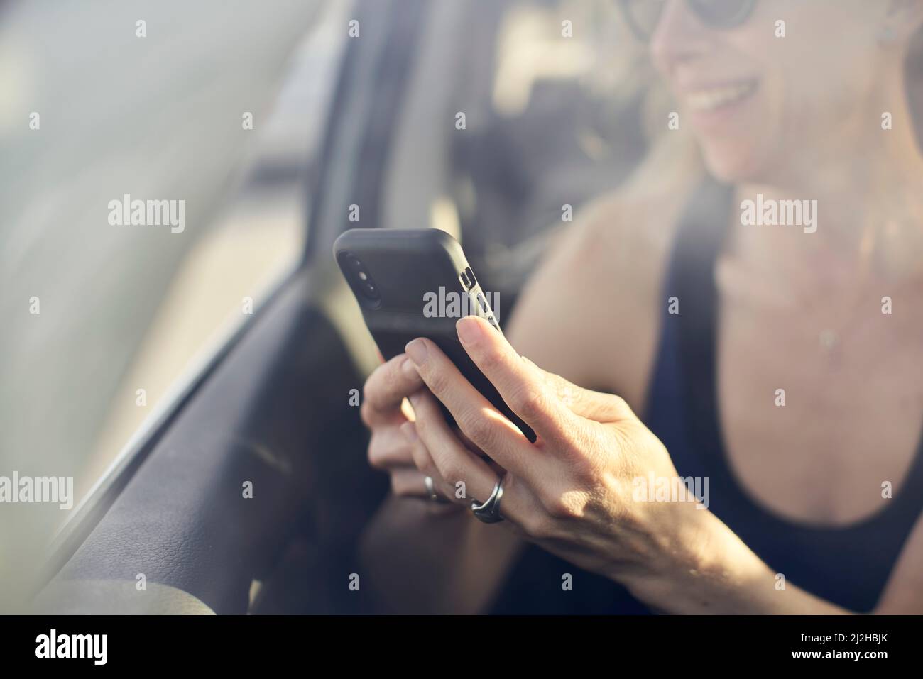 Femme mûre souriante utilisant un smartphone en voiture Banque D'Images