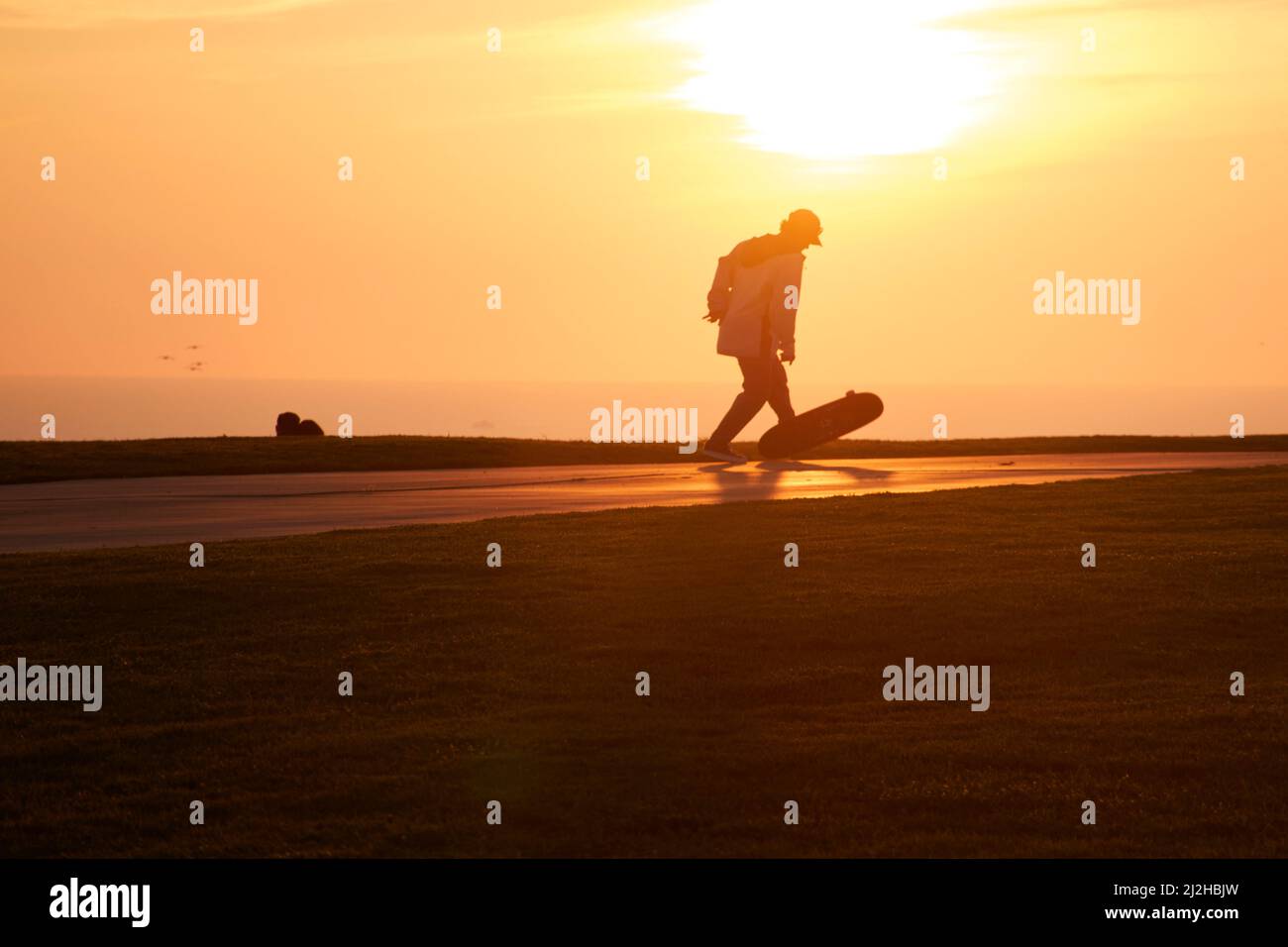 Homme mature skate au coucher du soleil Banque D'Images