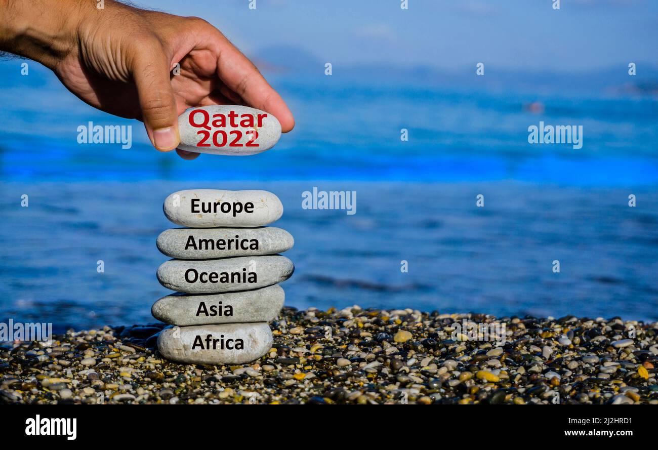 Homme main ajoutant la pierre de la coupe du monde du Qatar 2022 à la tour de pierre du continent. Le plus grand tournoi de football du monde commence. Banque D'Images