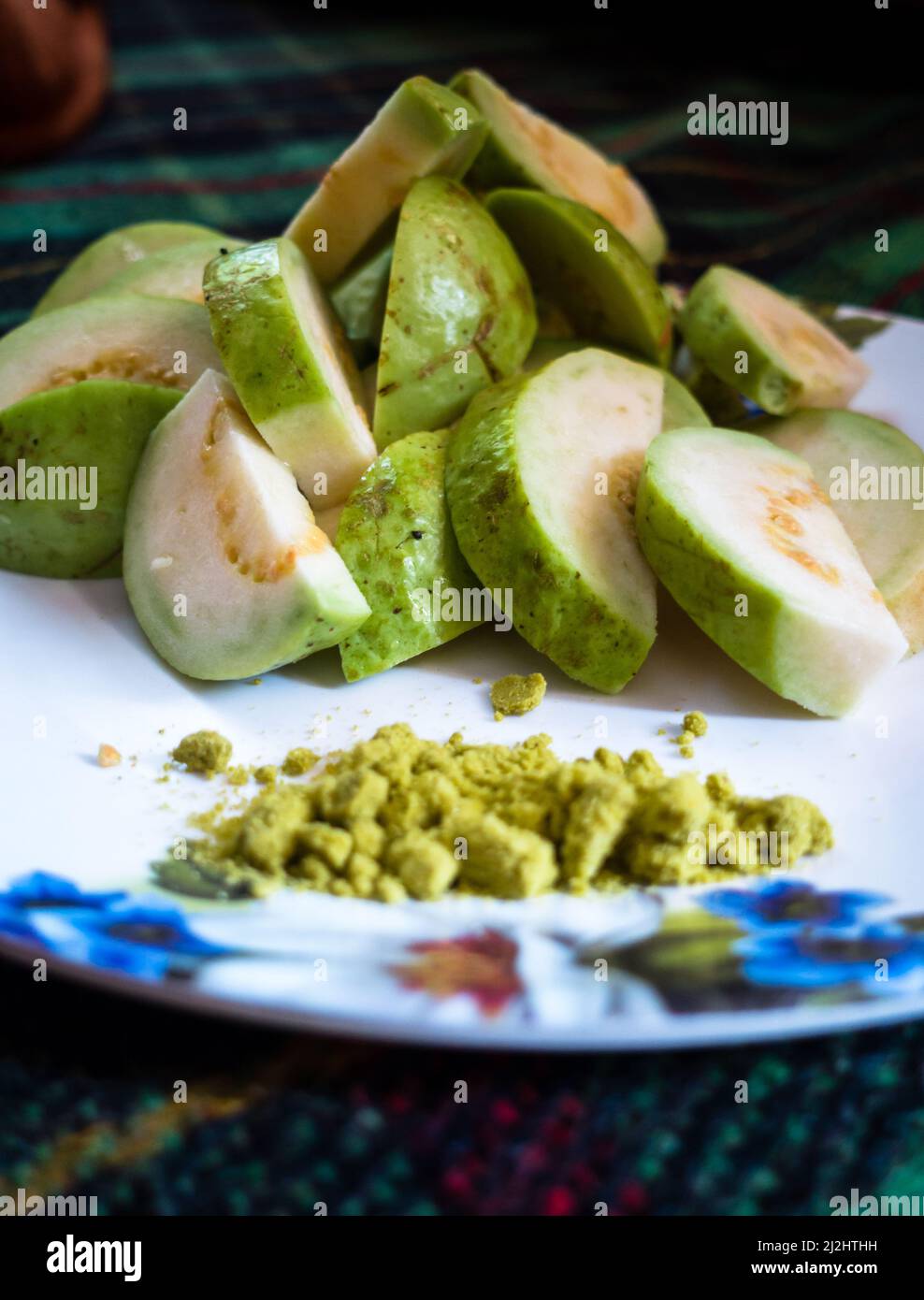 Un gros plan de salade de goyave servi avec un mélange indien de sel vert sur une assiette blanche. Banque D'Images