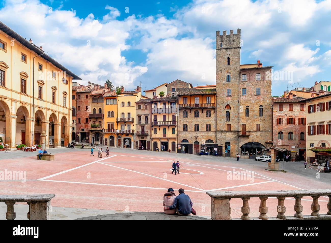 Couple assis au sol sur la célèbre place Piazza Grande dans le centre historique d'Arezzo, Italie Banque D'Images