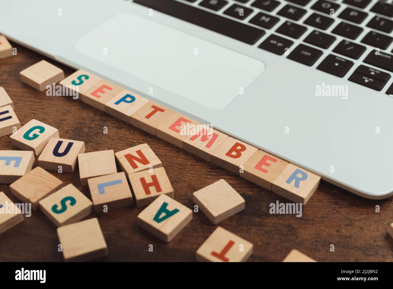 Septembre fait de lettres en bois coloré jeu de vocabulaire sur la table à côté de l'espace de copie d'ordinateur portable. Photo de haute qualité Banque D'Images