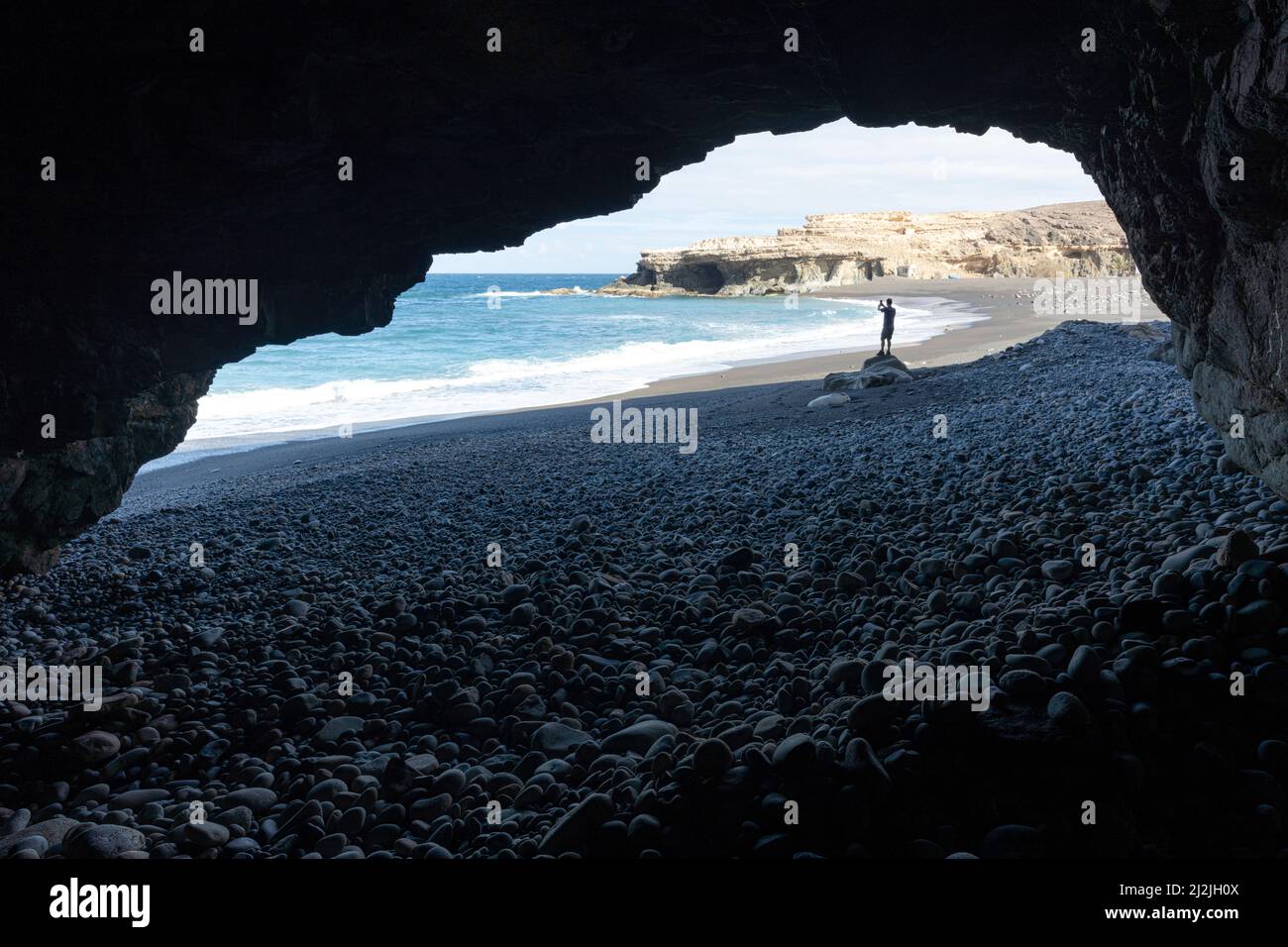 Silhouette de personne photographiant la mer avec vue smartphone depuis une grotte de mer, Ajuy, Fuerteventura, îles Canaries, Espagne Banque D'Images