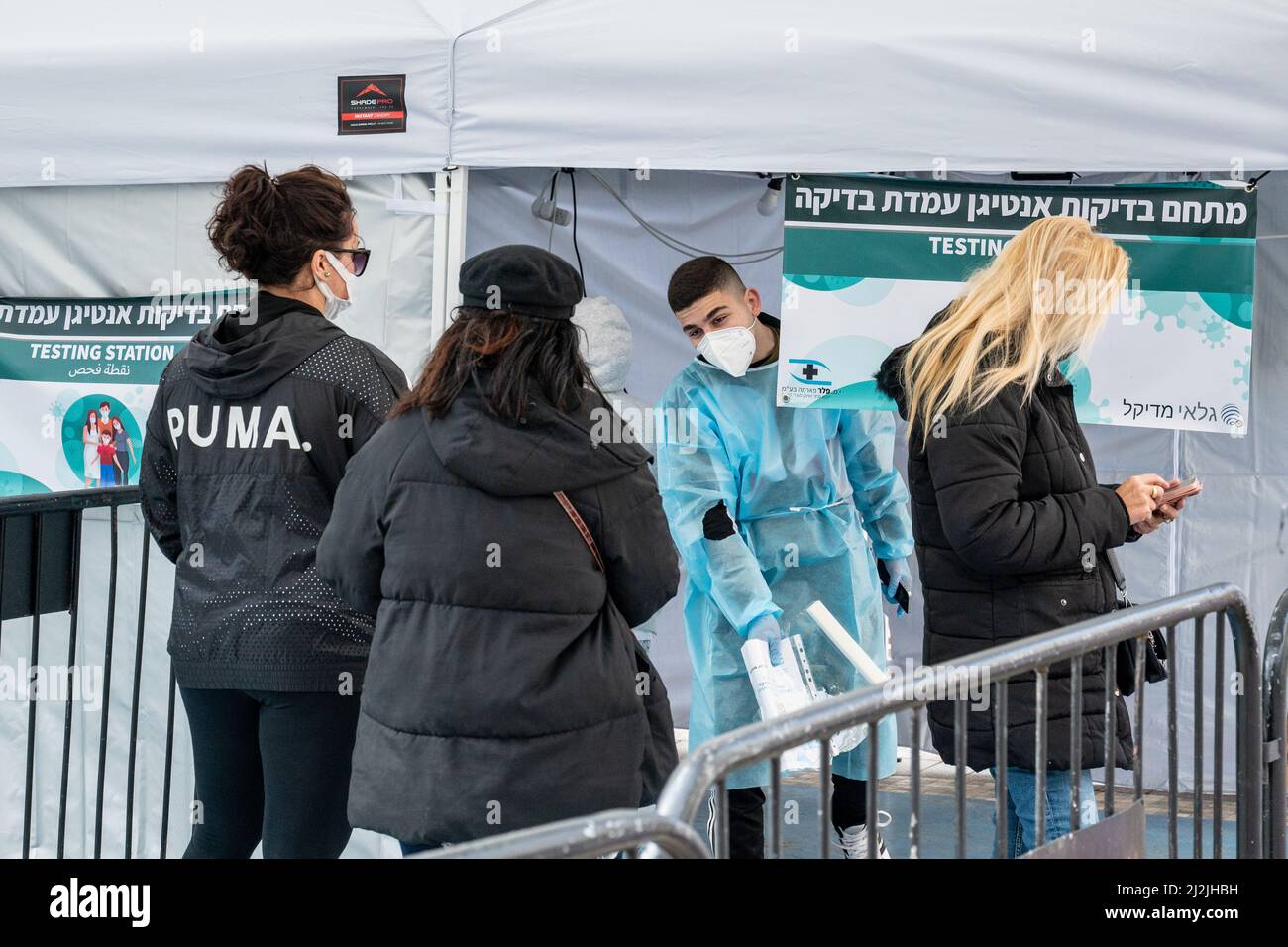 Netanya, Israël, le 7 février 2022: Herzel Street.Un ambulancier en équipement de protection individuelle l'EPI reçoit des personnes pour la vaccination. COVID-19 pandémie o Banque D'Images