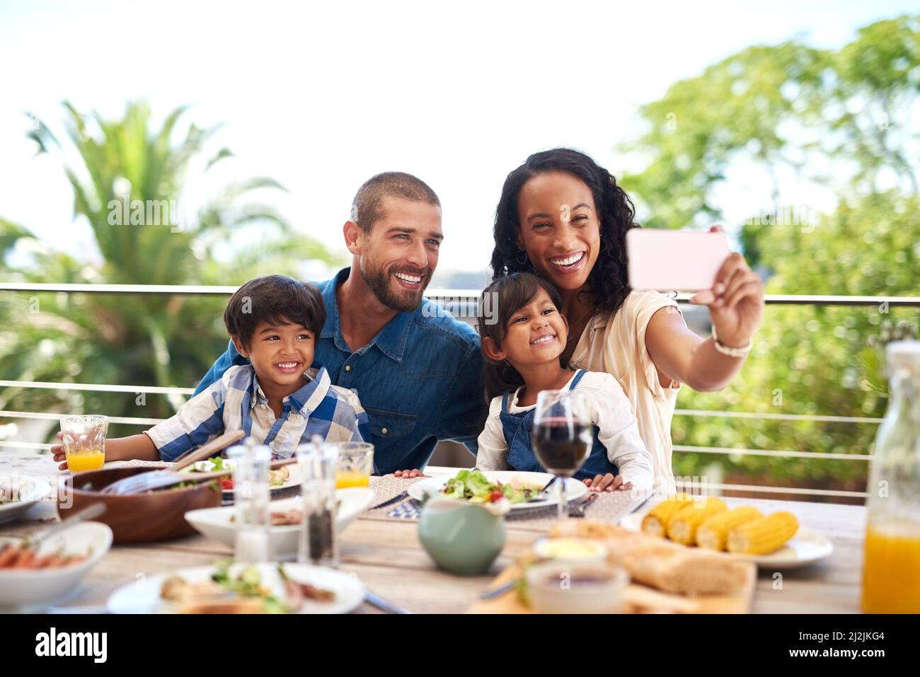 Notre belle petite famille est parfaite. Photo d'une belle jeune famille prenant des photos avec un téléphone portable tout en dégustant un repas ensemble Banque D'Images