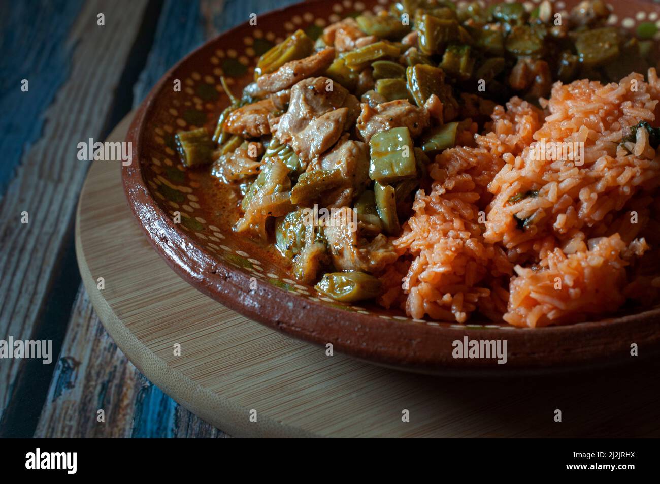 Porc. Cuisine mexicaine, poulet aux nopales et riz mexicain aux tortillas de maïs faites à la main sur une plaque de boue ou d'argile, sur une planche à découper ronde en bois. Banque D'Images