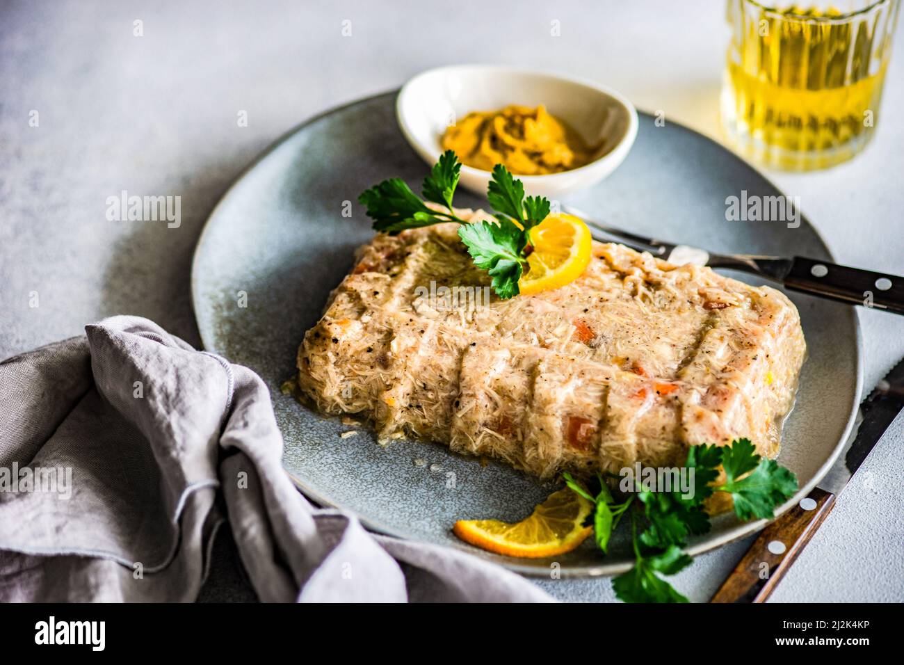 Pate de poulet sur une assiette avec persil, citron, moutarde et un verre de vin blanc Banque D'Images