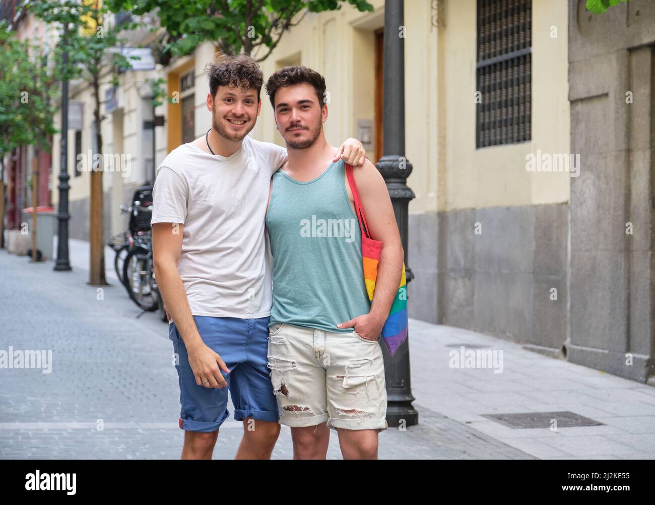 Un couple gay souriant se serre et regarde la caméra dans la rue. Banque D'Images