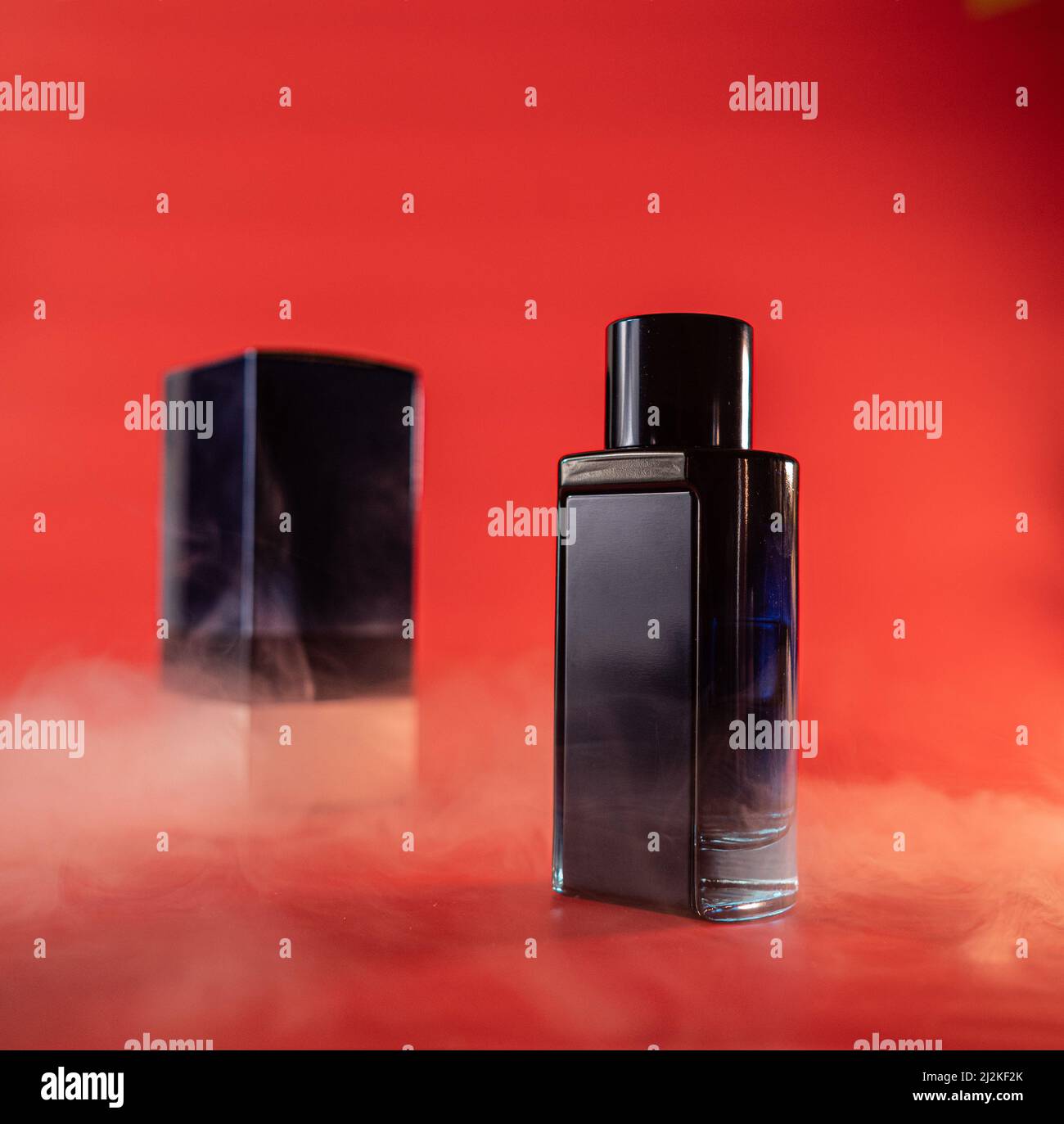 bouteille bleue d'eau parfumée sur fond rouge avec éléments de fumée Banque D'Images