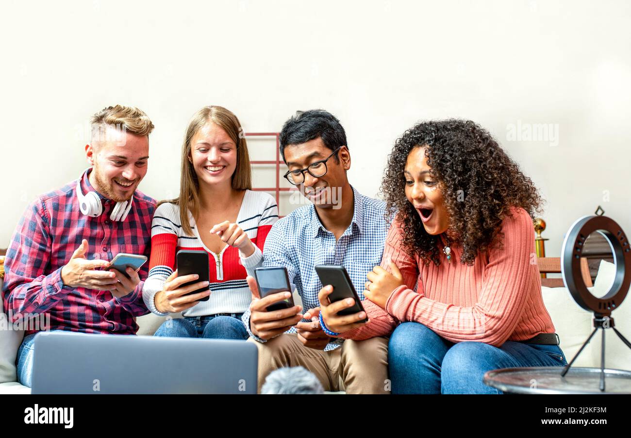 groupe de jeunes créateurs de contenus regardant les smartphones leur réalisation en ligne, quatre personnes blogueurs travaillant en studio pour les entreprises, travail d'équipe de jeunes Banque D'Images