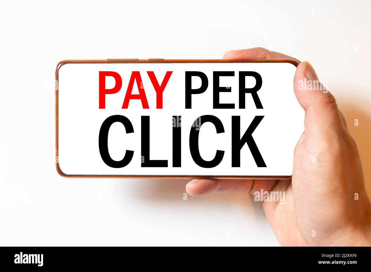 CPC coût par message de clic sur la main tenant pour toucher un téléphone, vue de dessus, ordinateur de table café et livre. Banque D'Images