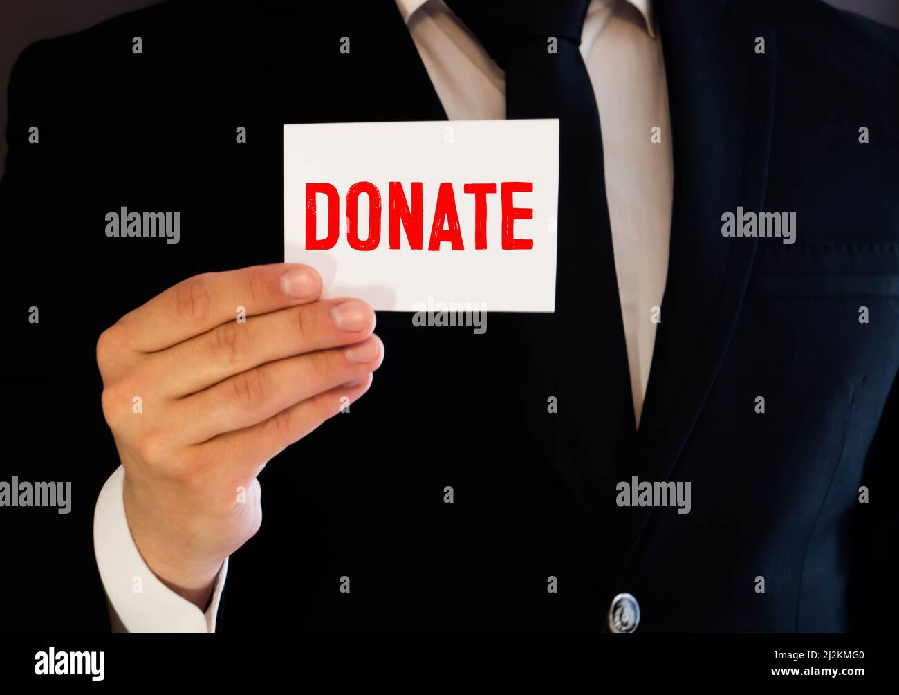Le concept médical de don de mot écrit en lettres rouges sur un morceau de papier blanc dans les mains d'un homme d'affaires. Banque D'Images