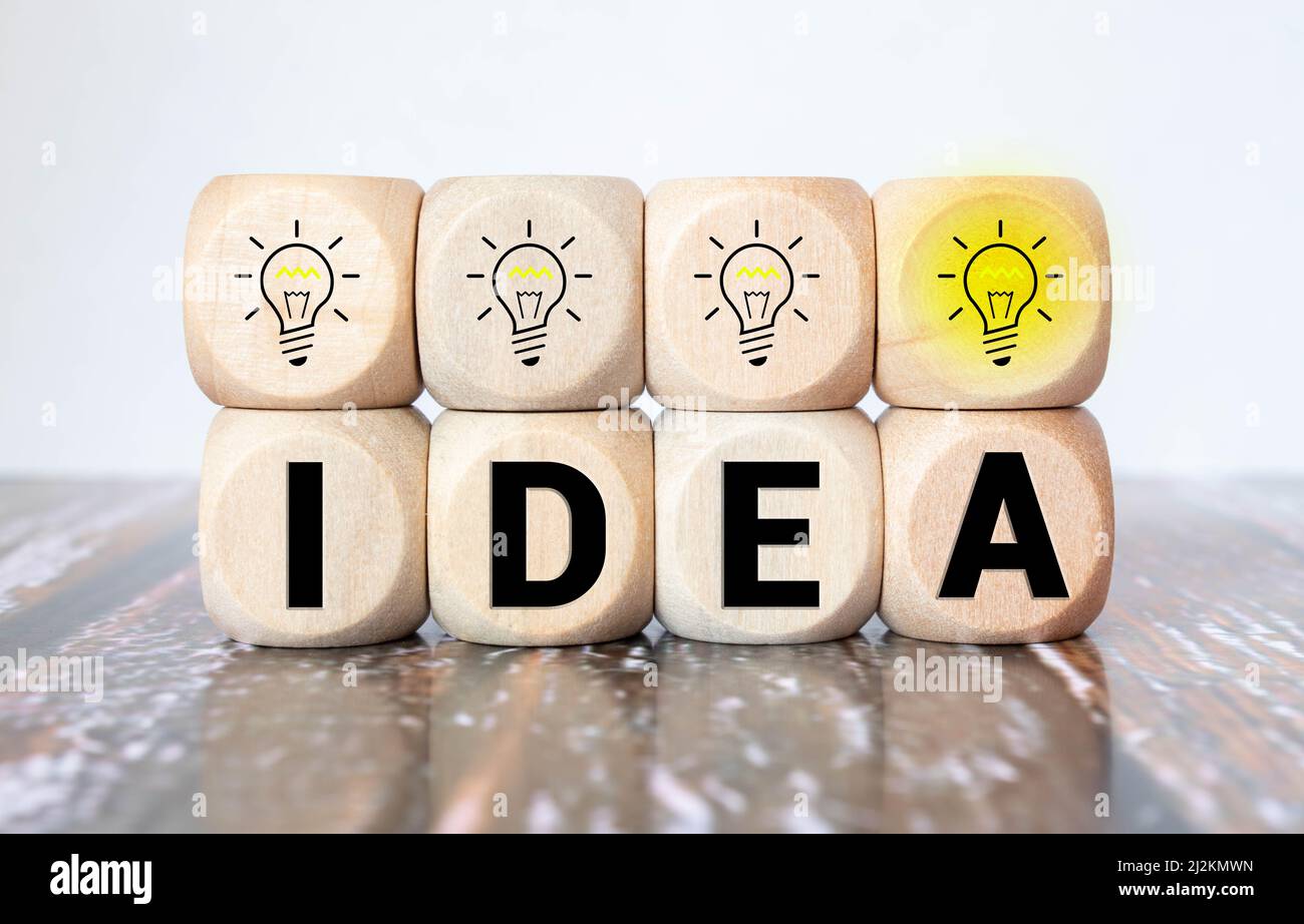 Concept idée créative et innovation. Retournez à la main le bloc cube en bois avec le symbole de la tête humaine et l'icône de l'ampoule Banque D'Images