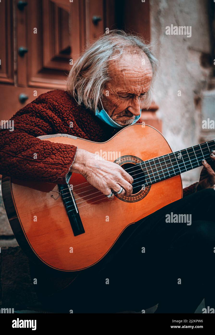 Un vieil homme avec une guitare assis devant un bâtiment au Portugal Banque D'Images