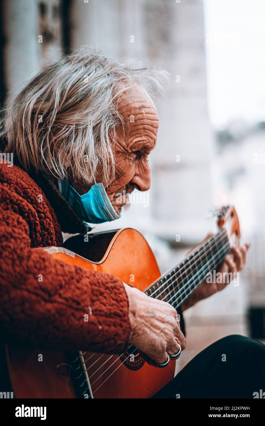 Un vieil homme avec une guitare assis devant un bâtiment au Portugal Banque D'Images