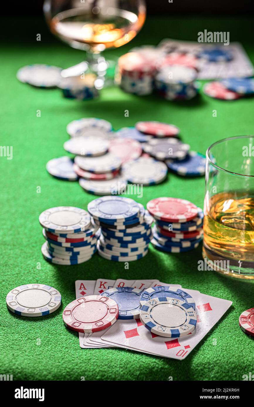 Table de jeux de poker avec whisky, cartes et jetons. Verre de bourbon avec glace sur table de jeu avec cartes et jetons. Banque D'Images