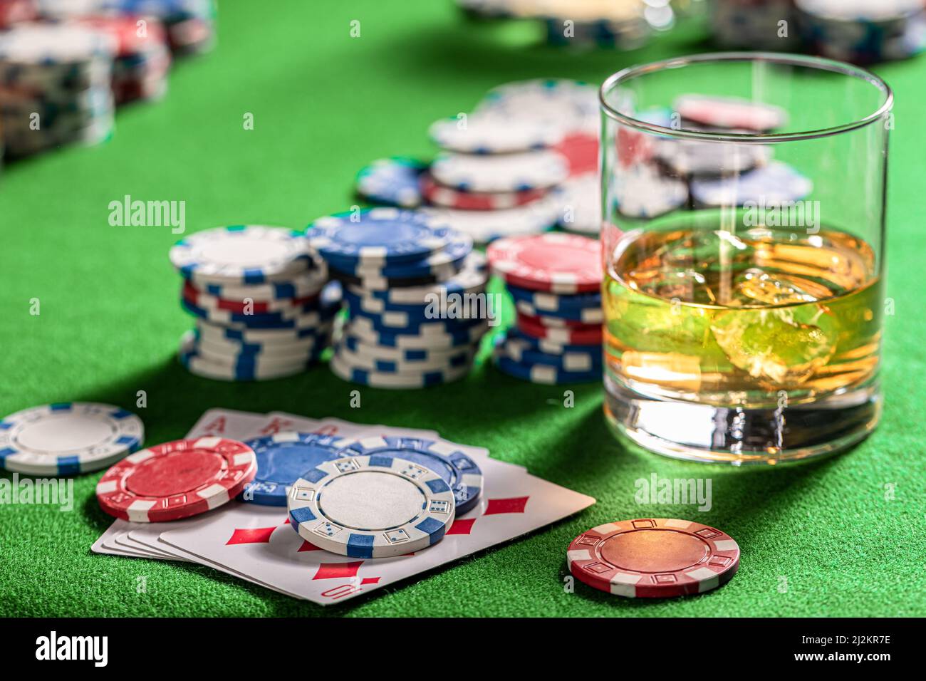 Table de jeu verte avec cartes, jetons et chiksy. Table de poker avec cartes, jetons et un verre de whisky avec glace. Banque D'Images