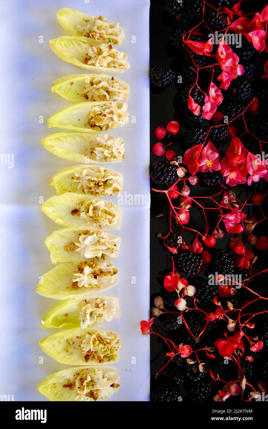 Enplongées remplies de mousse au fromage sur un plateau décoré de mûres et de fleurs comestibles Banque D'Images Enplongées remplies de mousse au fromage sur un plateau décoré de mûres et de fleurs comestibles Banque D'Images